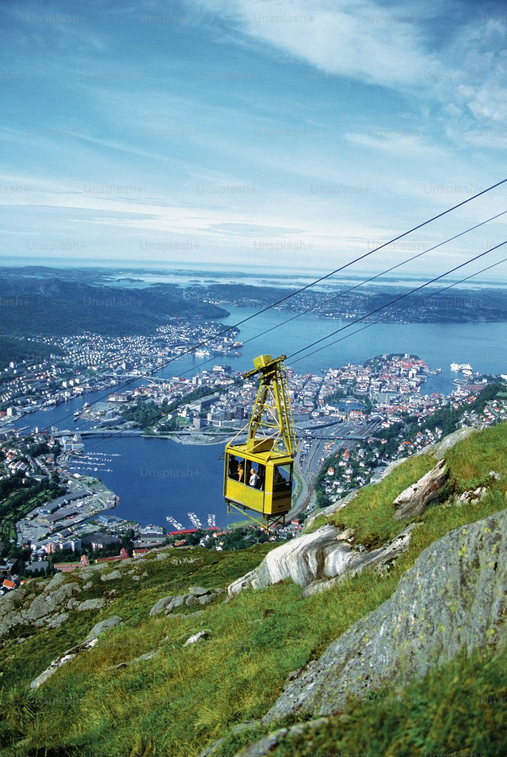 um teleférico amarelo subindo uma colina com uma cidade ao fundo