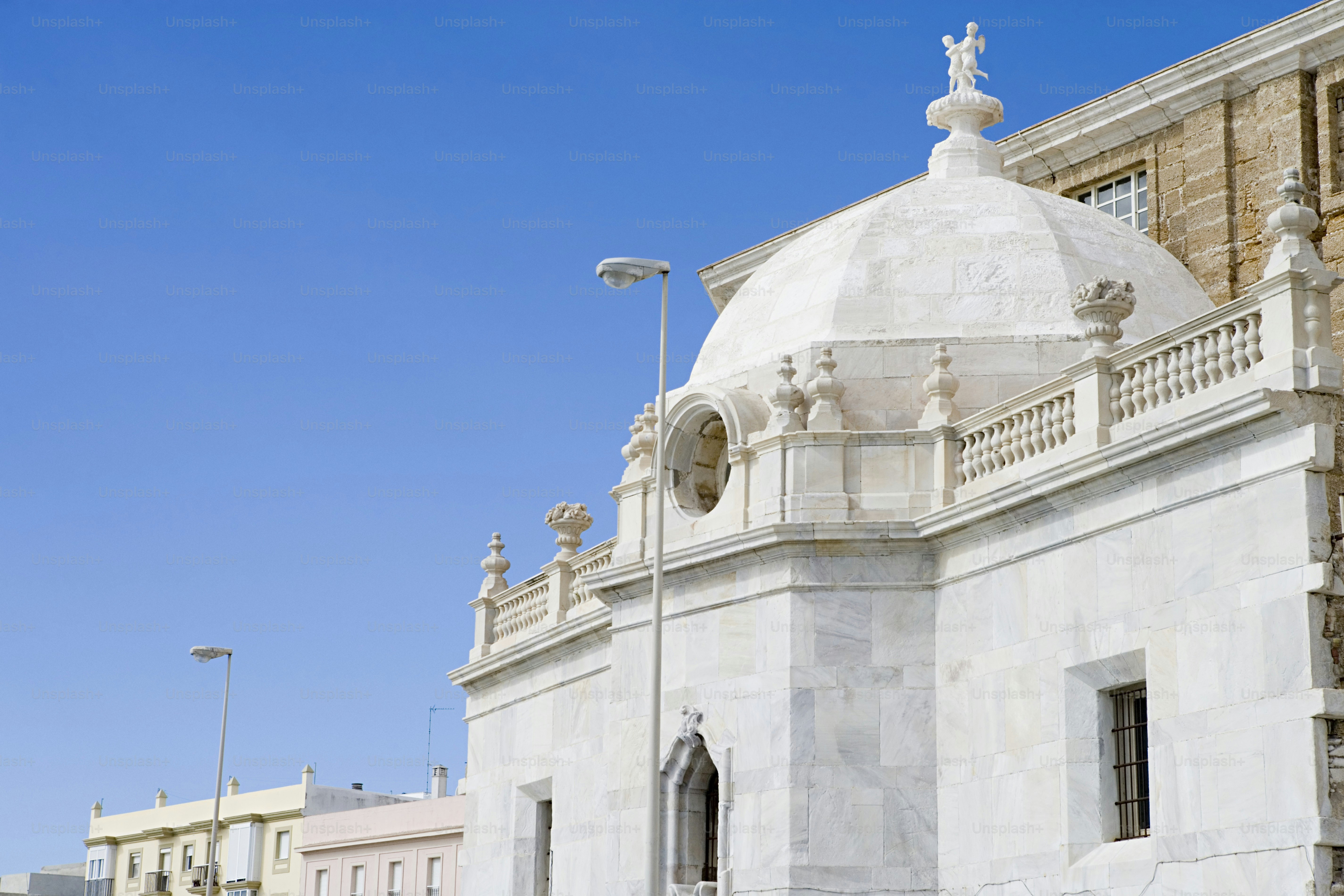 A large white building with a clock on the top of it photo – Built ...