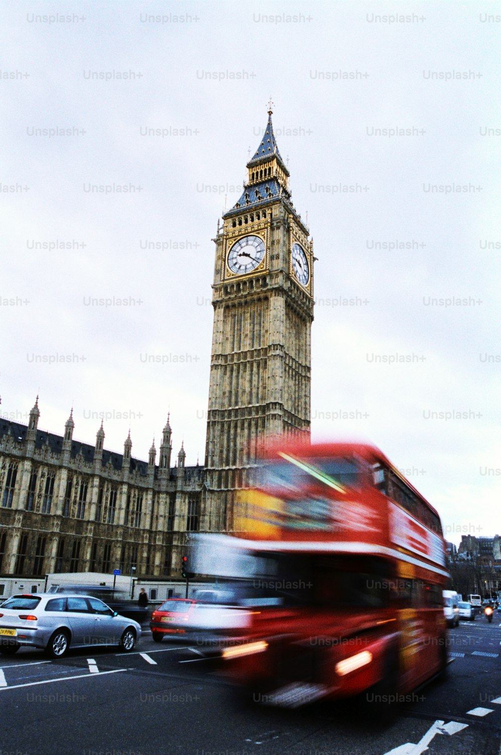 a red double decker bus driving past big ben