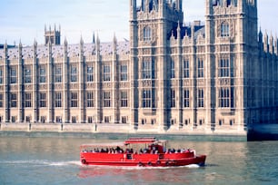 a red boat in the water near a large building