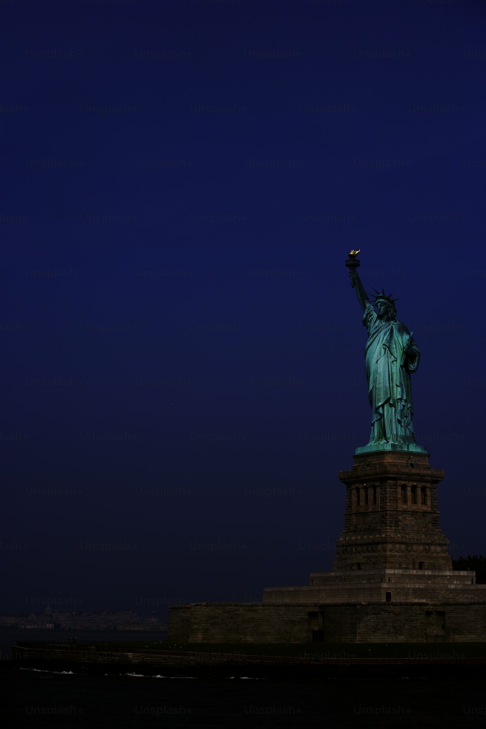 the statue of liberty stands on the edge of a body of water