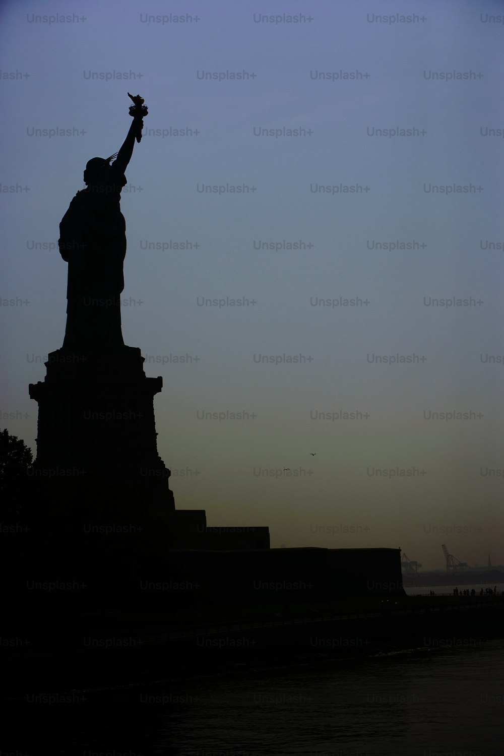 the statue of liberty stands on the edge of a body of water