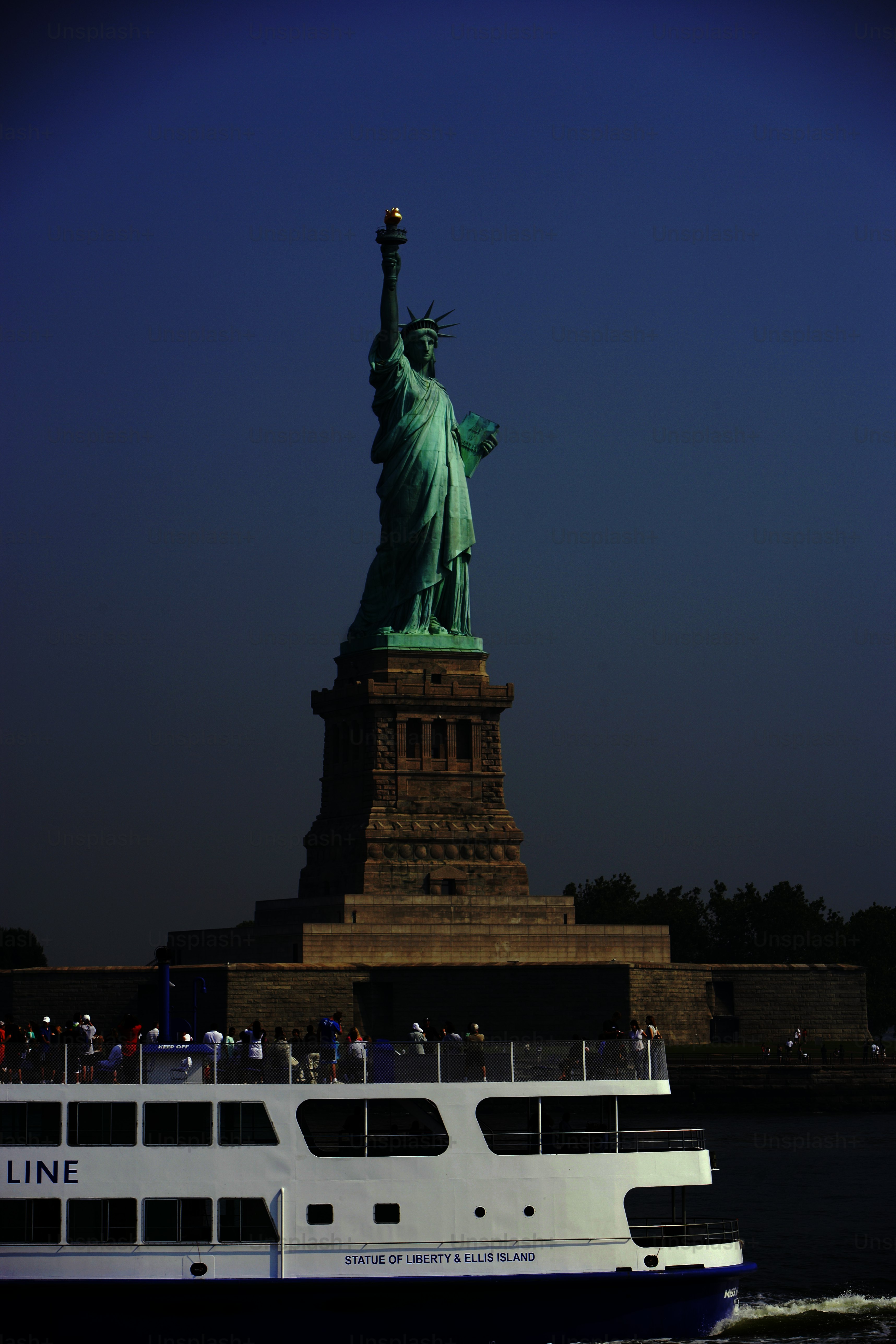 a large boat in the water near a statue of liberty