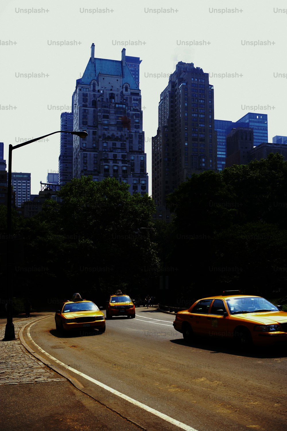a group of taxi cabs driving down a street next to tall buildings