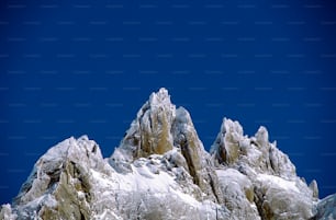 a very tall mountain covered in snow under a blue sky