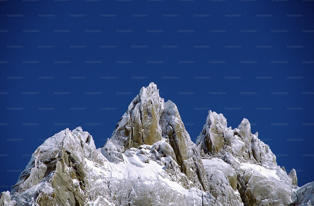 a very tall mountain covered in snow under a blue sky