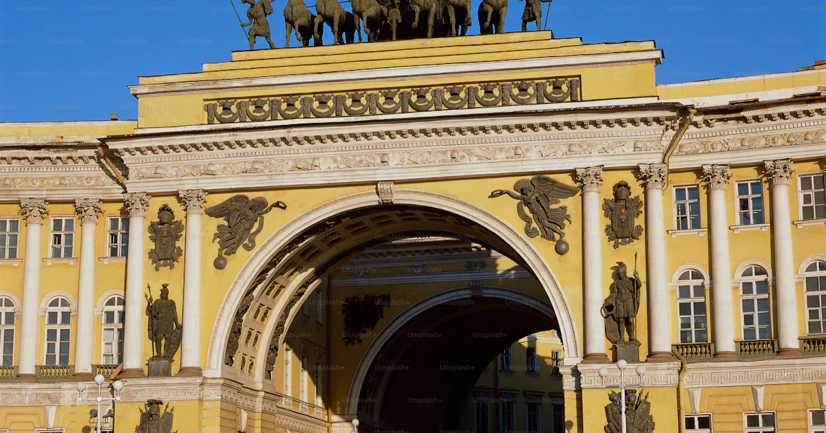 Famous Yellow Building A large yellow building with statues on top of it photo – Russian ...