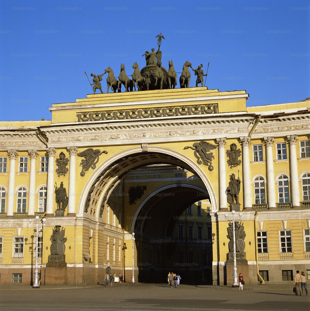 a large yellow building with statues on top of it