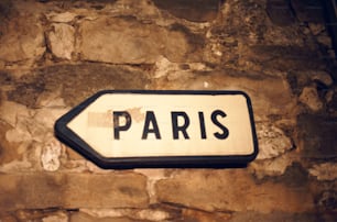 a white and black street sign on a stone wall