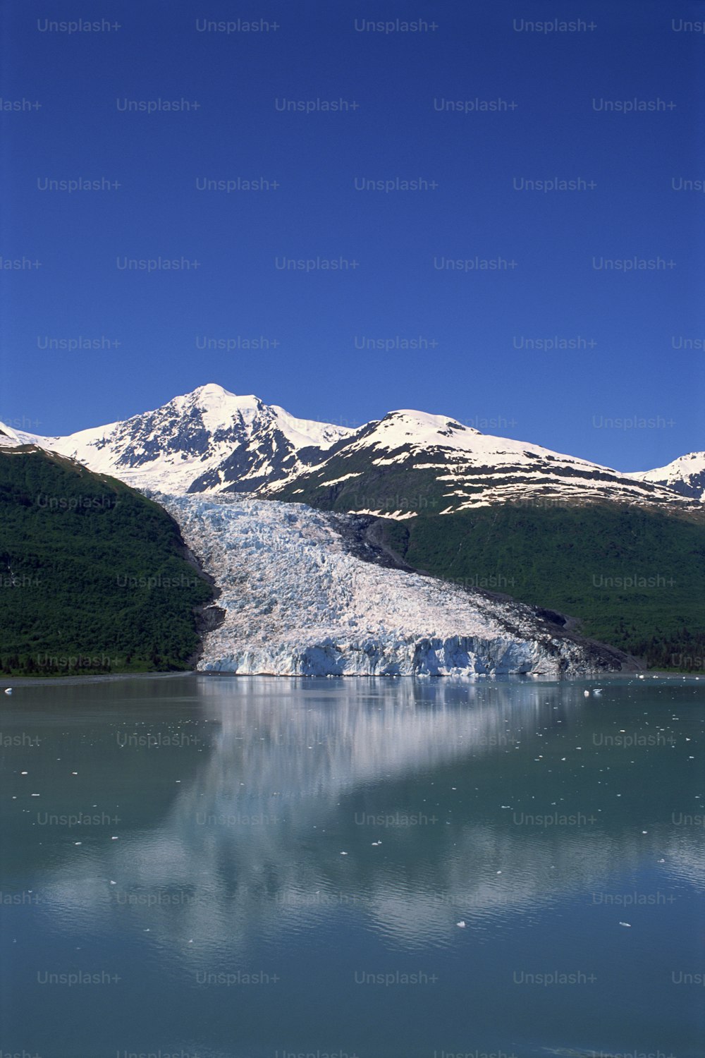 a glacier in the middle of a lake with mountains in the background