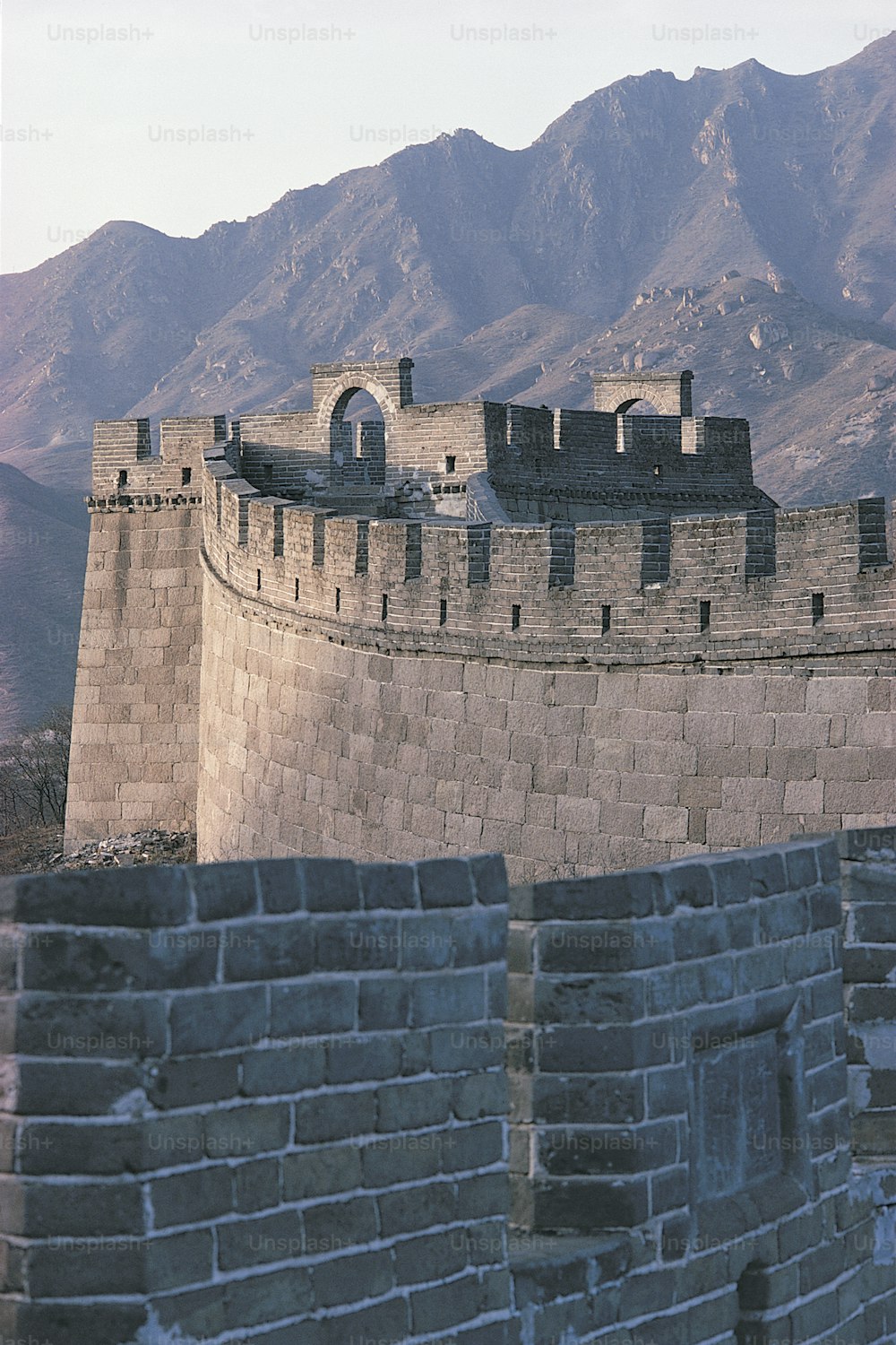 a large stone wall with mountains in the background