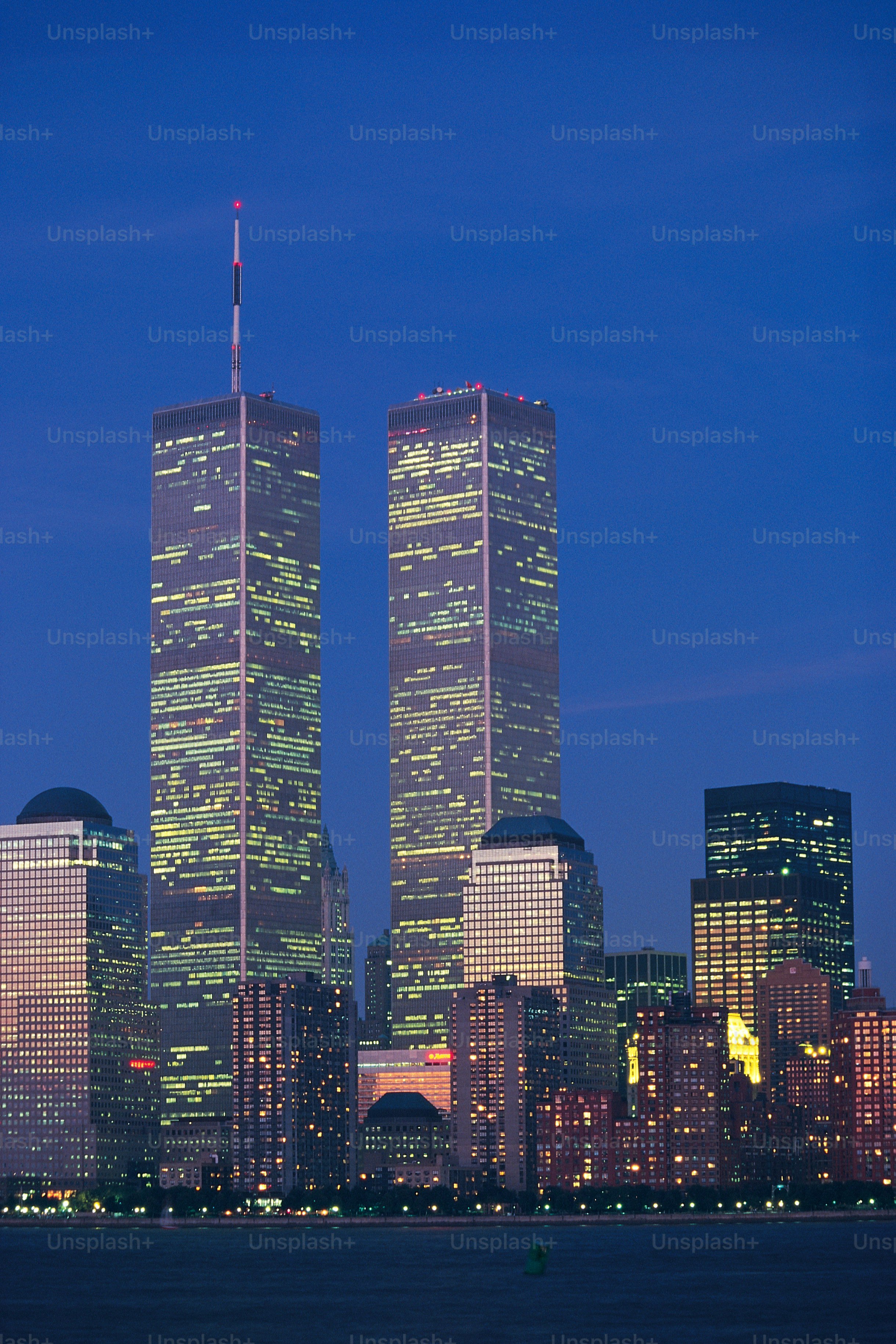 two skyscrapers are lit up at night in the city