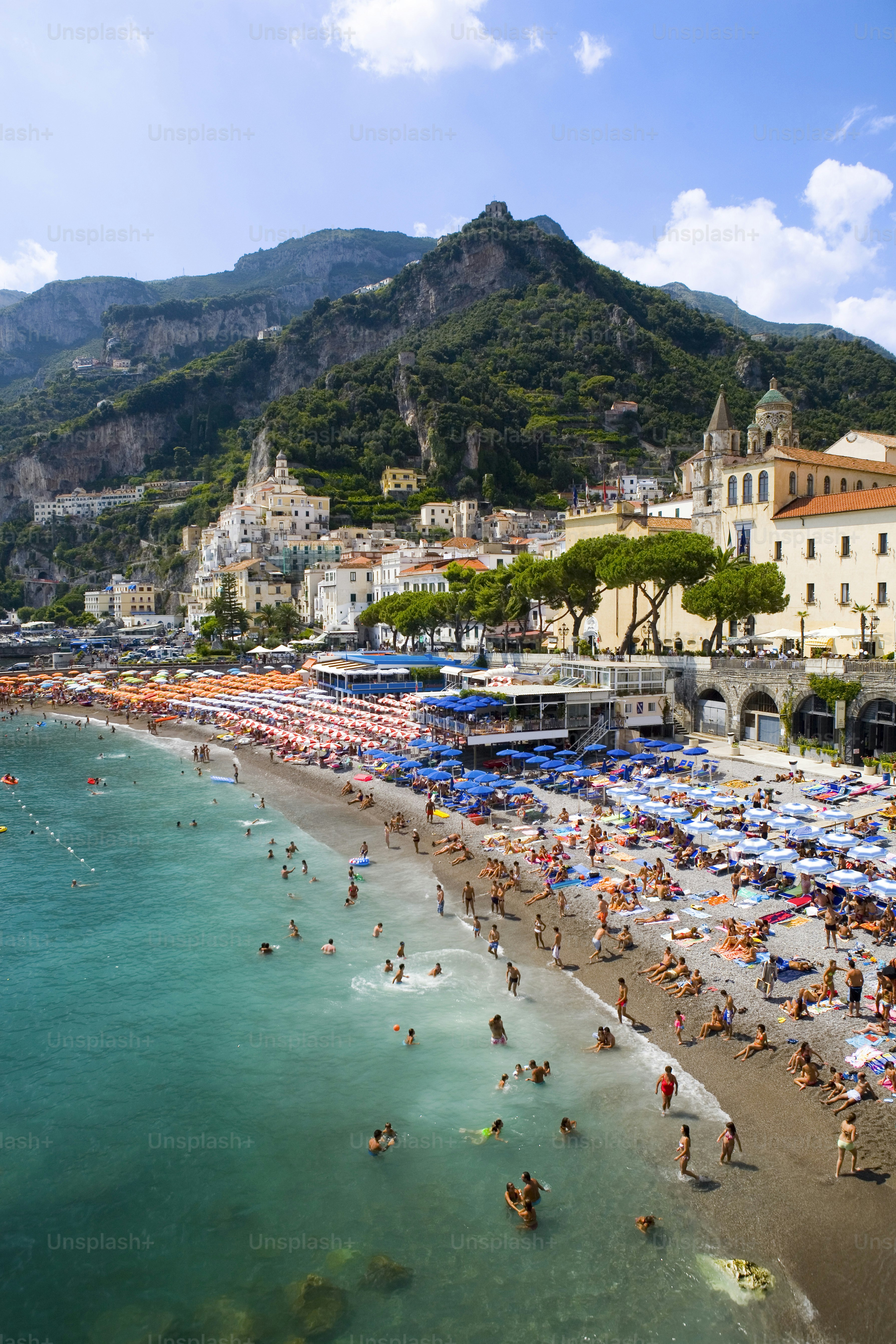 a crowded beach with umbrellas and people in the water