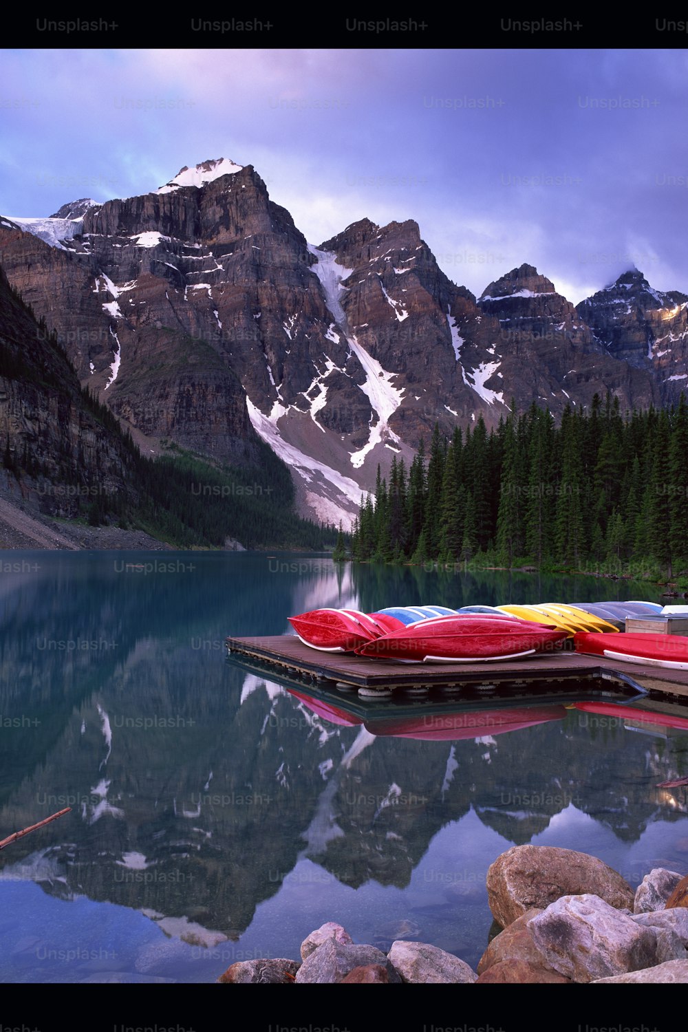 a lake surrounded by mountains with a row of canoes on it