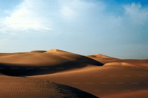a large group of sand dunes under a blue sky