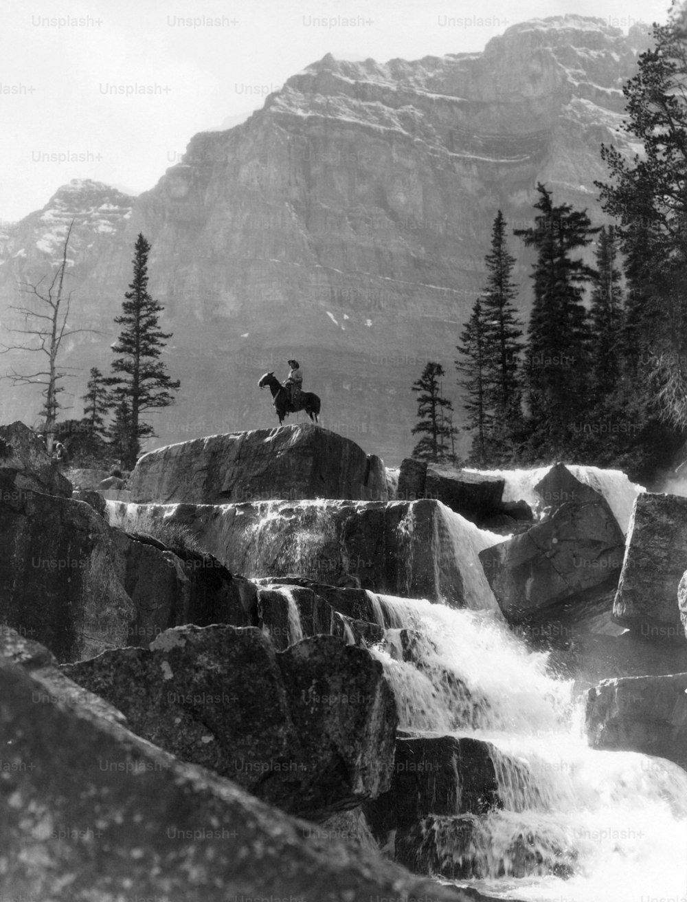 ESTADOS UNIDOS - Alrededor de la década de 1940: Cascada vertical Hombre a caballo en el fondo Gigantes Pasos Paradise Valley Alberta Canadá Montañas vaqueras Frontera solo remoto.