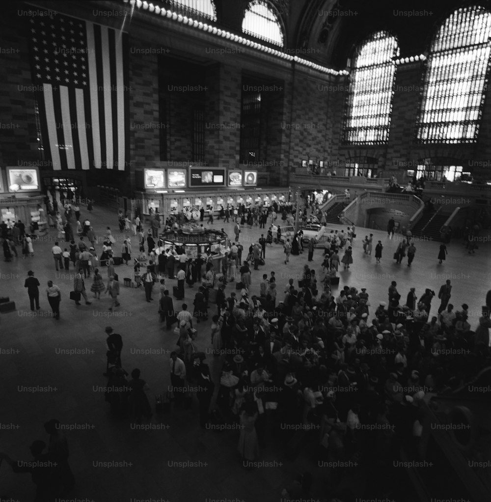 a black and white photo of people in a train station