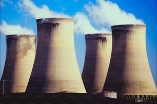 three cooling towers with smoke coming out of them