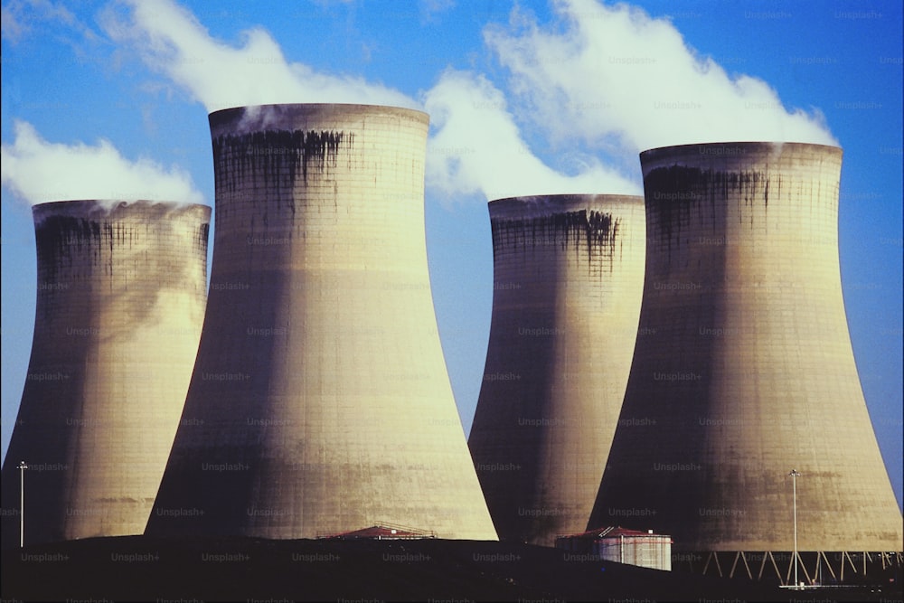 three cooling towers with smoke coming out of them