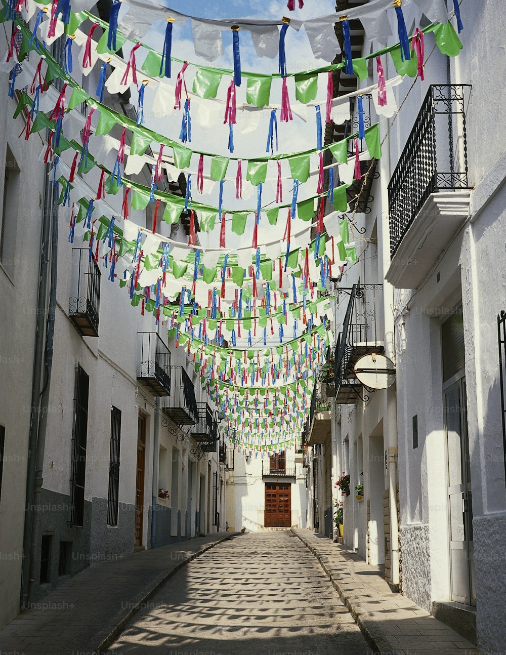 uma rua estreita com um monte de bandeiras penduradas nela