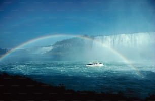 ein Boot im Wasser mit einem Regenbogen im Hintergrund