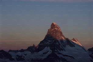 Una montagna innevata molto alta con uno sfondo del cielo