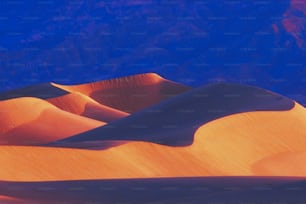 a view of a sand dune with mountains in the background
