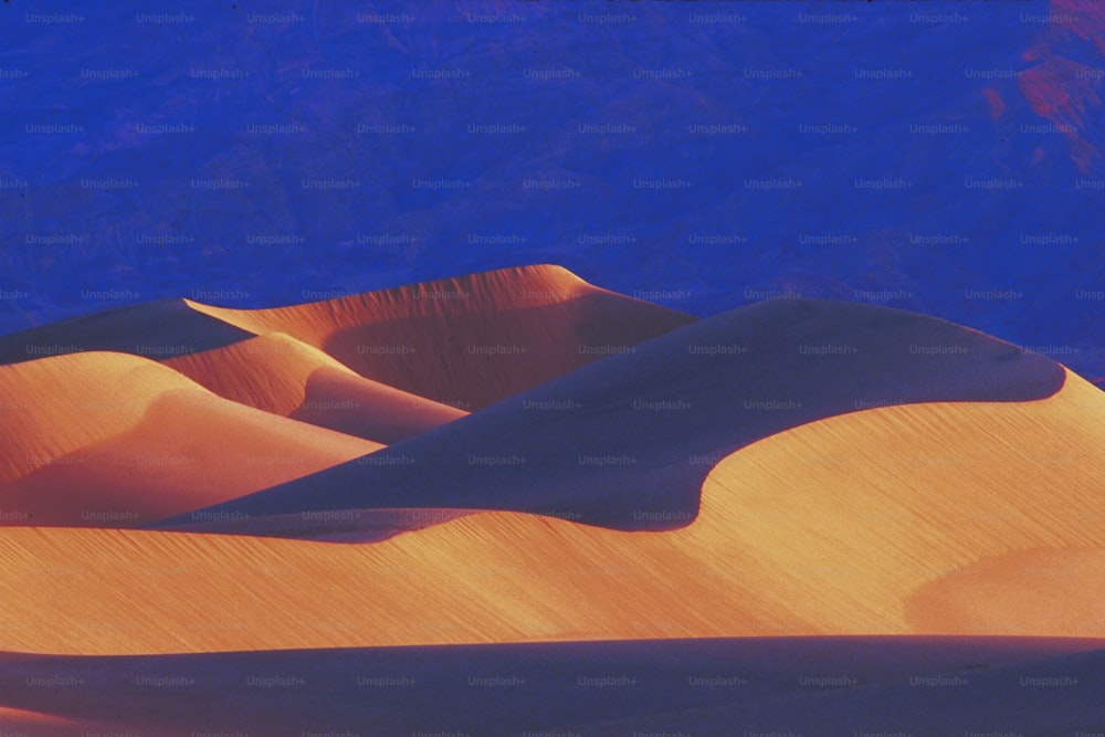 a view of a sand dune with mountains in the background