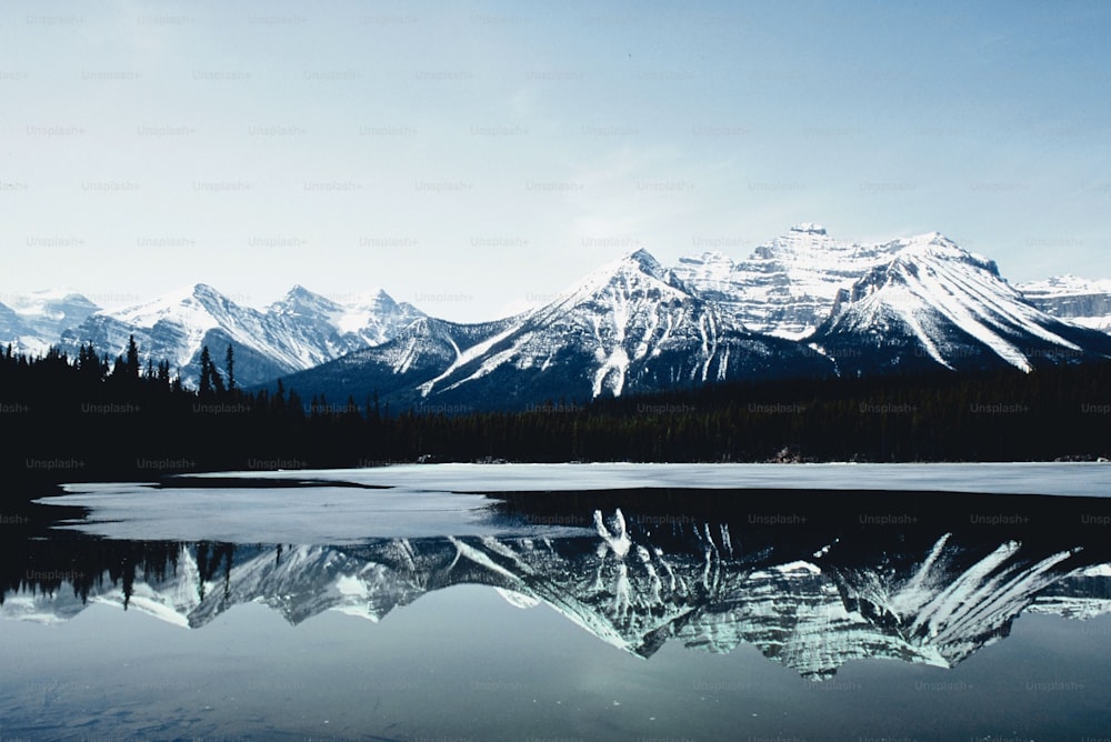 a mountain range is reflected in the still water of a lake