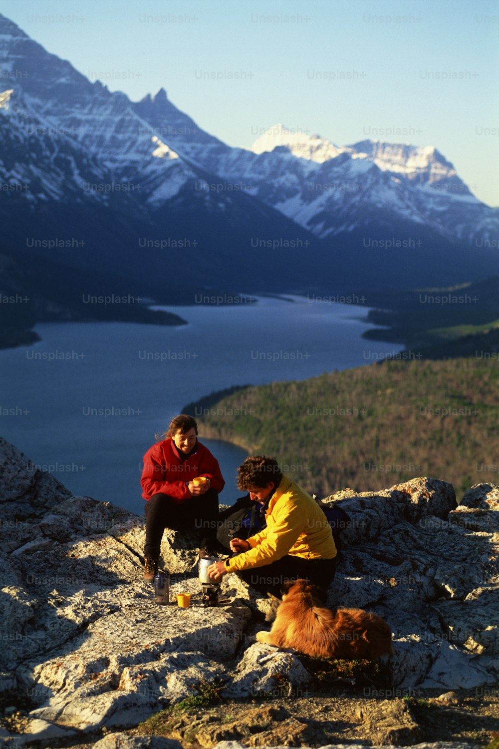Un par de personas sentadas en la cima de una montaña