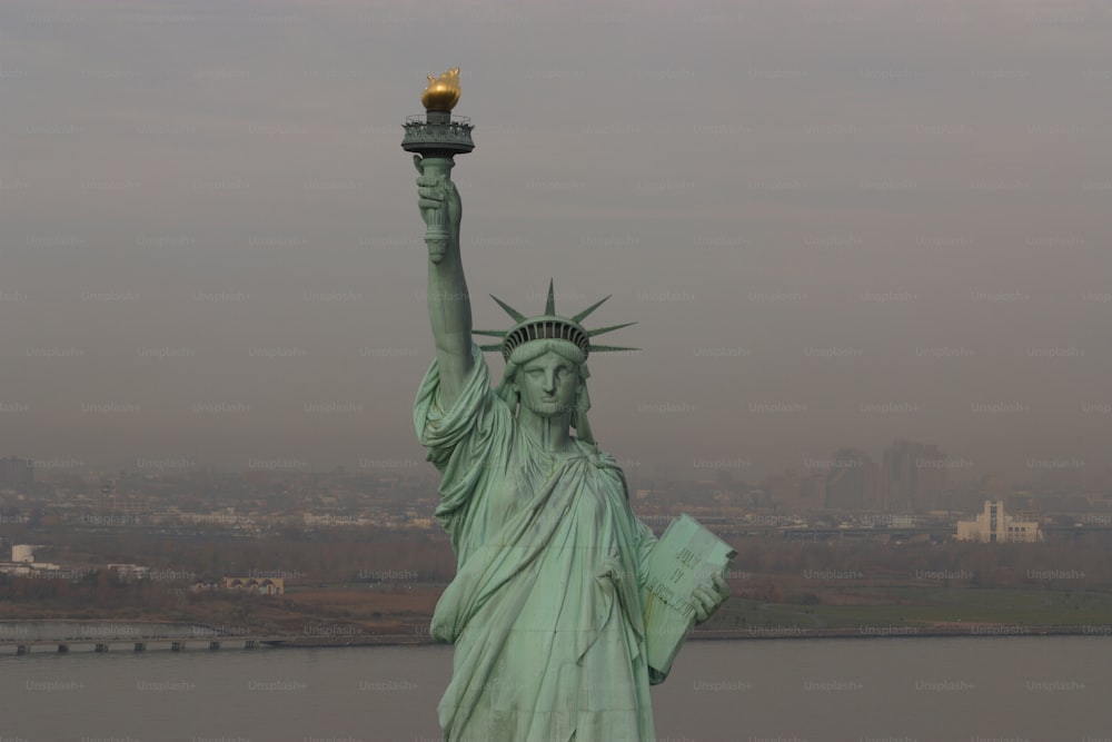 the statue of liberty stands in front of a body of water