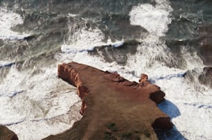 une vue aérienne de l’océan avec des vagues qui s’écrasent sur les rochers