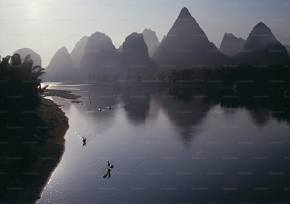 a body of water surrounded by mountains and birds