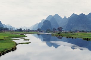 a body of water surrounded by mountains and grass