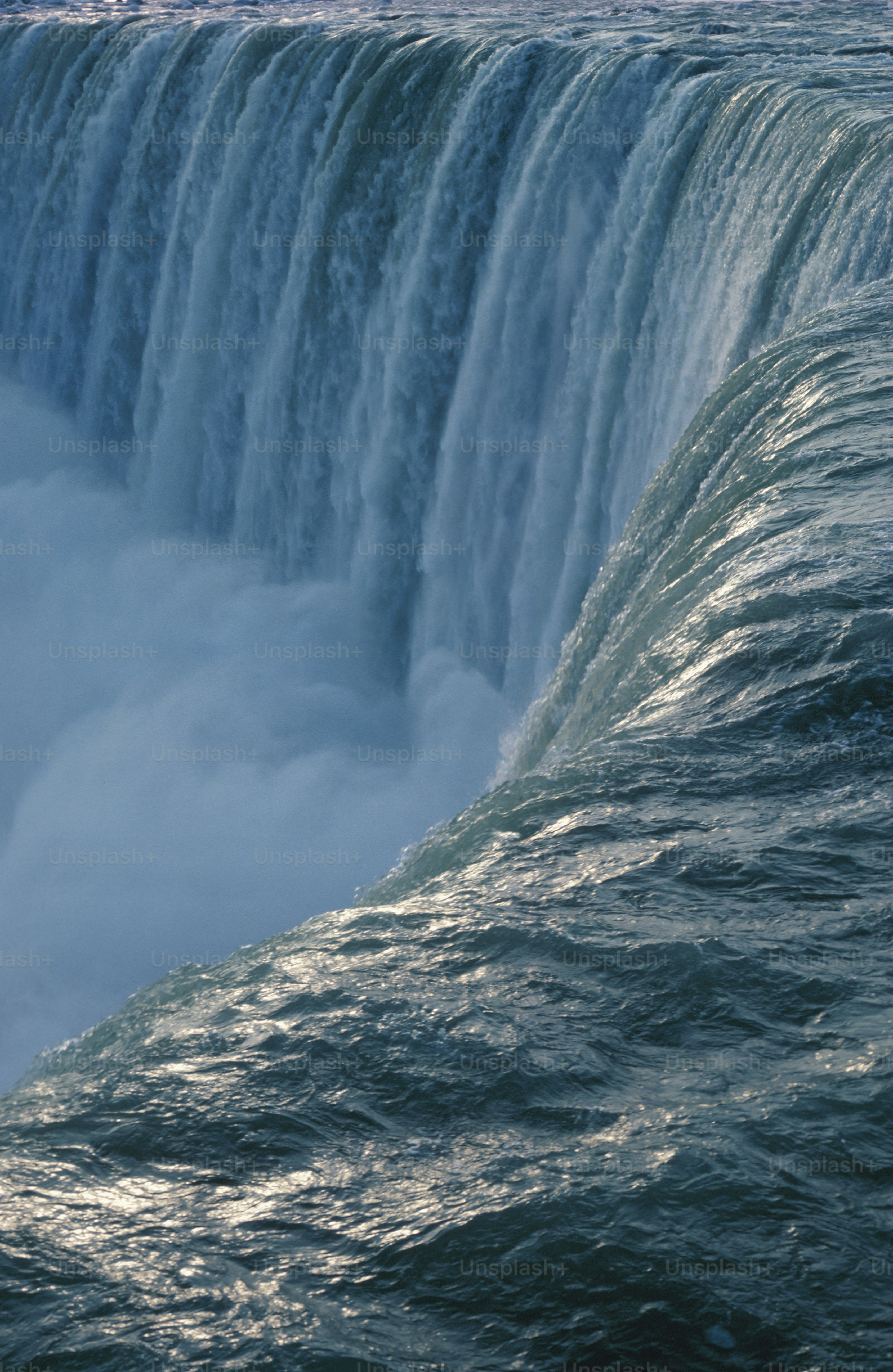 a man riding a surfboard on top of a large waterfall