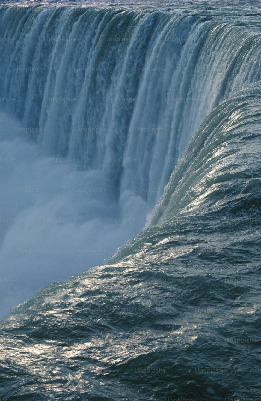 a man riding a surfboard on top of a large waterfall