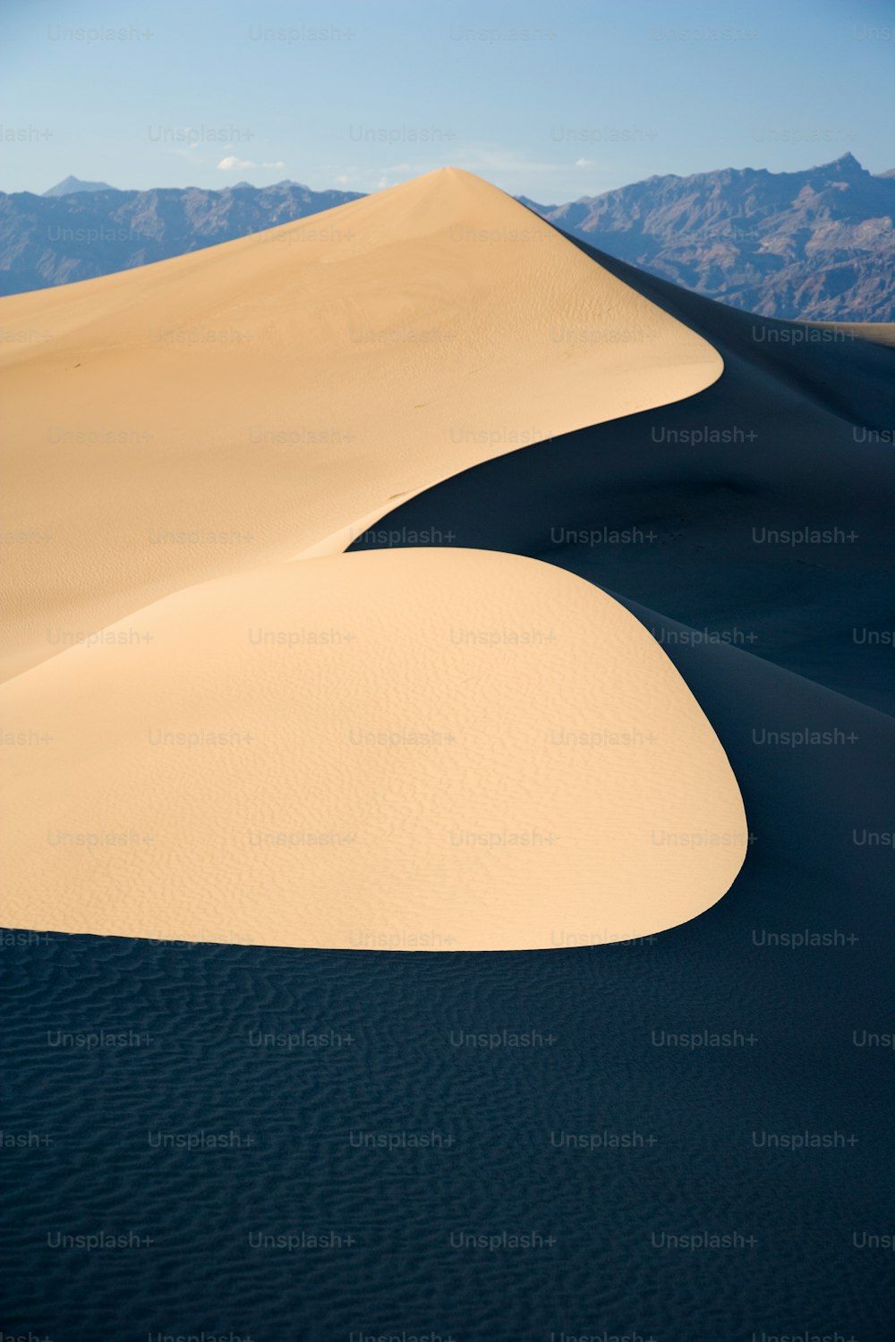 Una gran duna de arena con montañas al fondo