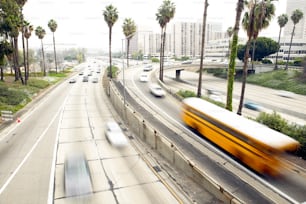 a yellow bus driving down a street next to palm trees