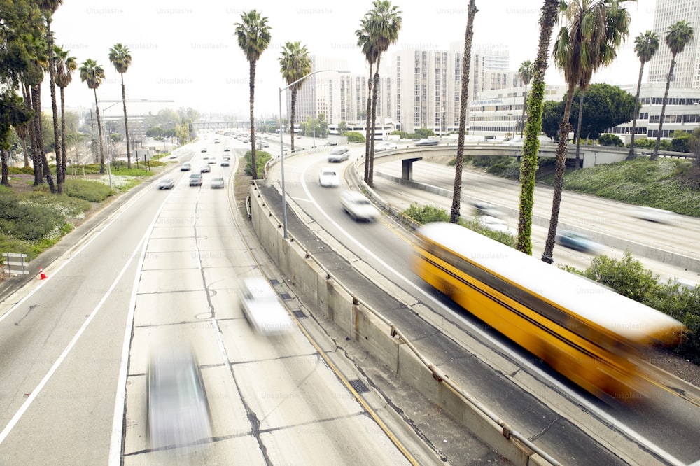 a yellow bus driving down a street next to palm trees