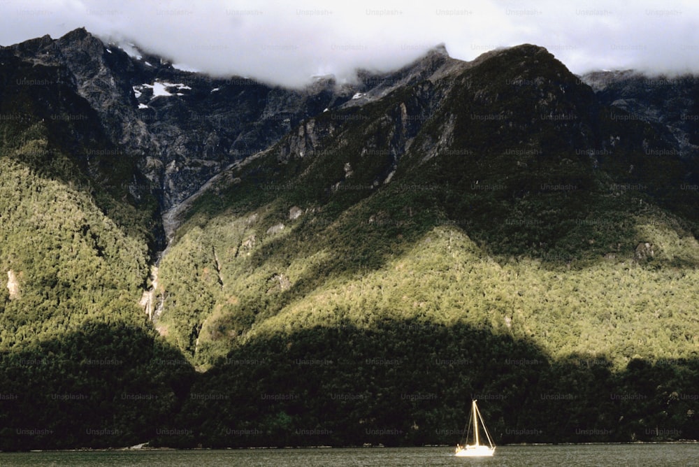 a sailboat on a body of water in front of a mountain range