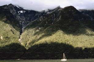un velero en un cuerpo de agua frente a una cadena montañosa