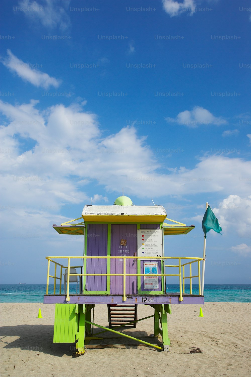 a purple and green life guard stand on a beach