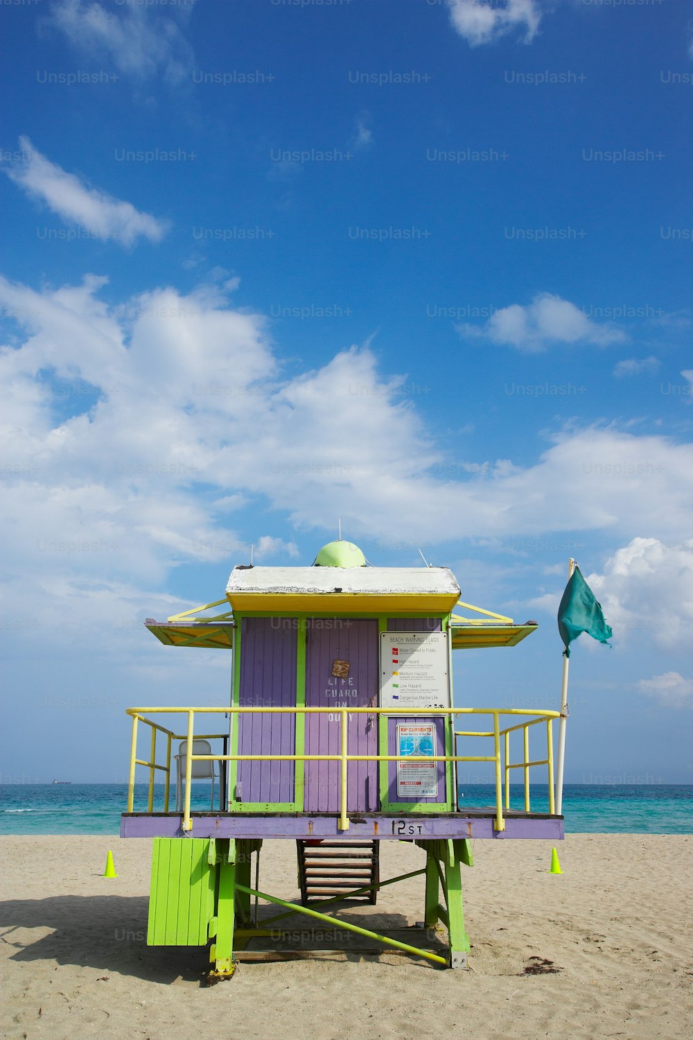 a purple and green life guard stand on a beach