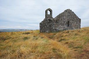 a stone building sitting on top of a grass covered hillside