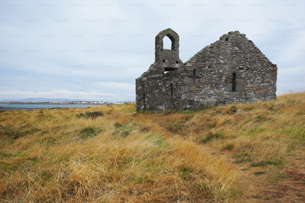 a stone building sitting on top of a grass covered hillside