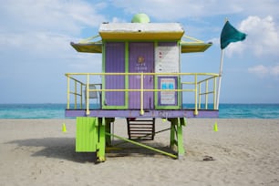 해변에 있는 보라색과 초록색 인명 구조원 타워