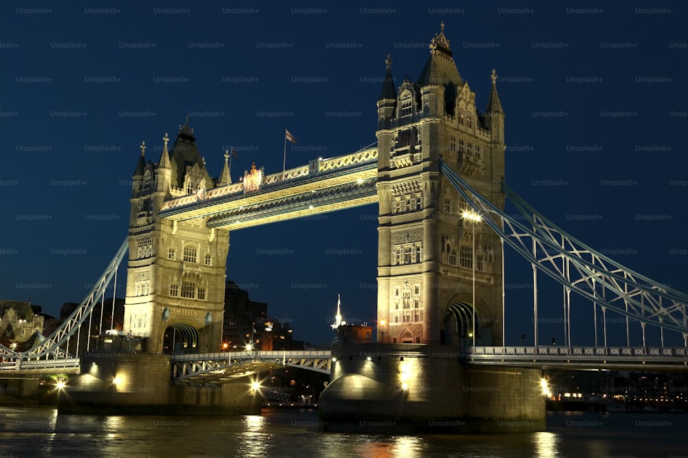 the tower bridge is lit up at night