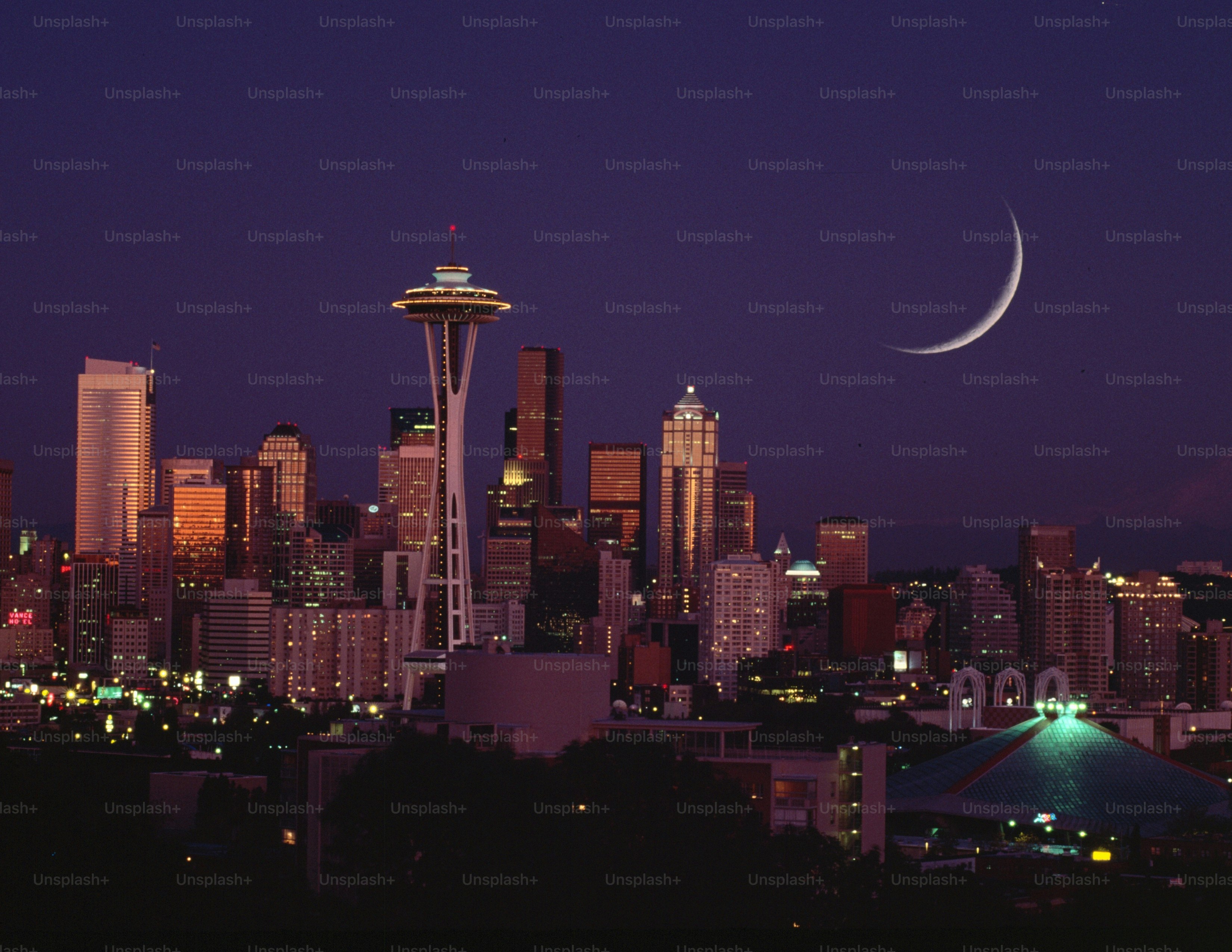 a view of a city at night with the moon in the sky