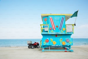 un poste de sauveteur sur la plage avec un camion jouet garé devant