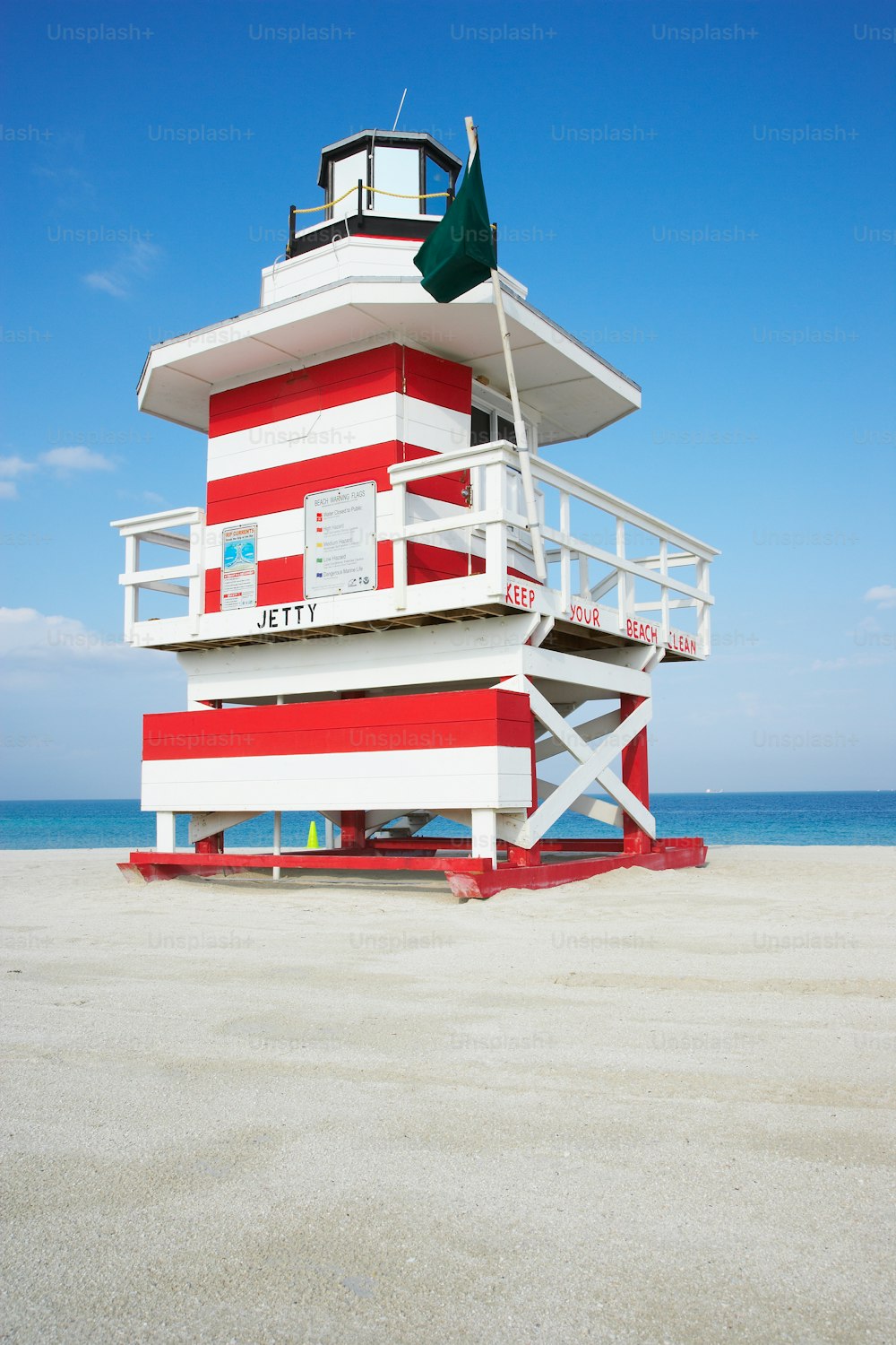 a red and white lifeguard tower on the beach